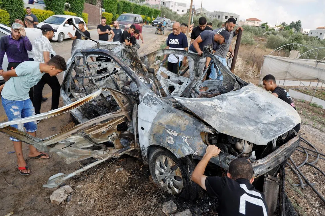 Palestinians inspecting a vehicle damaged in an Israeli airstrike, in Zeita, near Tulkarm, in the Israeli-occupied West Bank on Aug 3. 