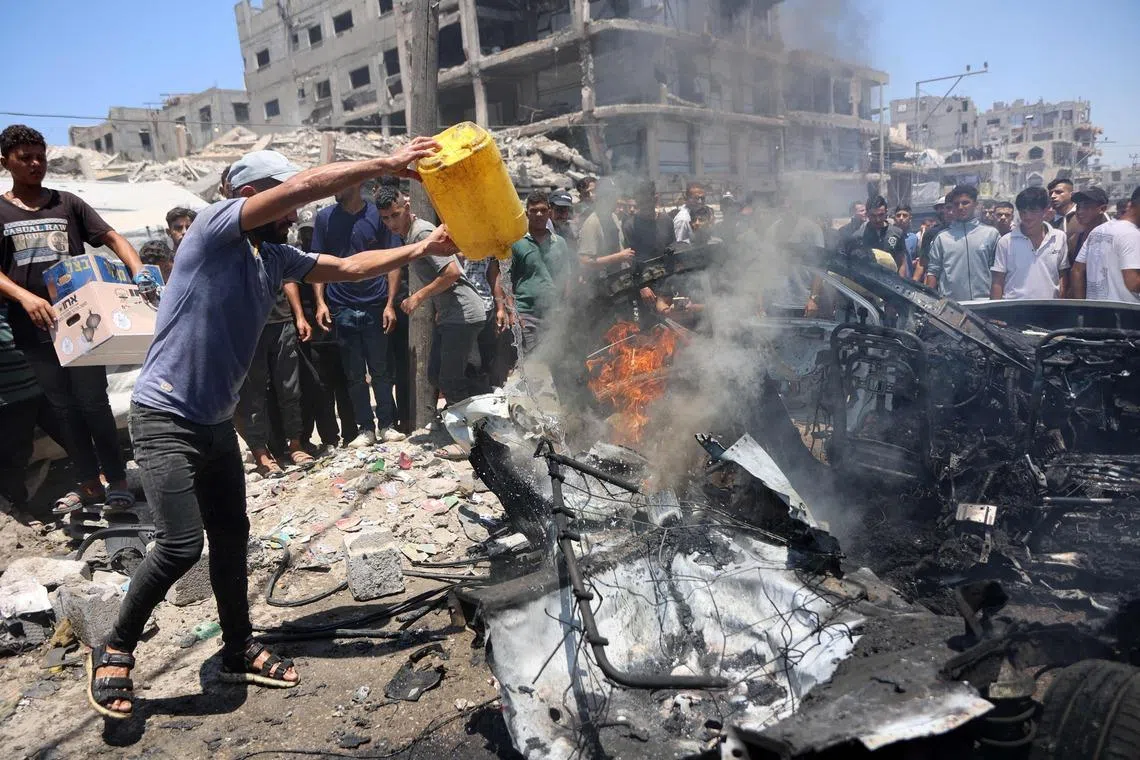 TOPSHOT - A displaced Palestinian tries to extinguish fire from a vehicle at the site of an Israeli strike in Gaza City on July 20, 2026. Violence has continued in Gaza despite the ceasefire. (Photo by Omar AL-QATTAA / AFP)