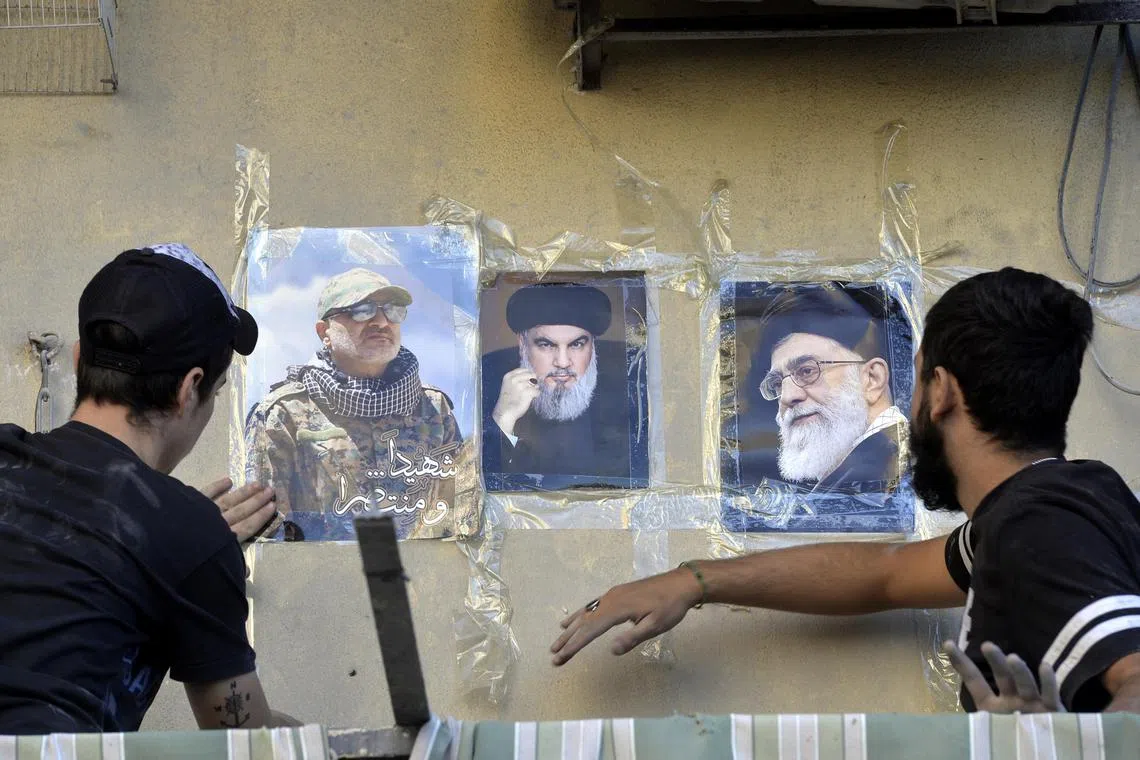 People place photos of late Hezbollah leader Hassan Nasrallah (centre) and Iranian Supreme Leader Ayatollah Ali Khamenei (right) on the wall of a building near the site of an Israeli airstrike in the Dahieh district, south of Beirut, Lebanon, on Oct 22.