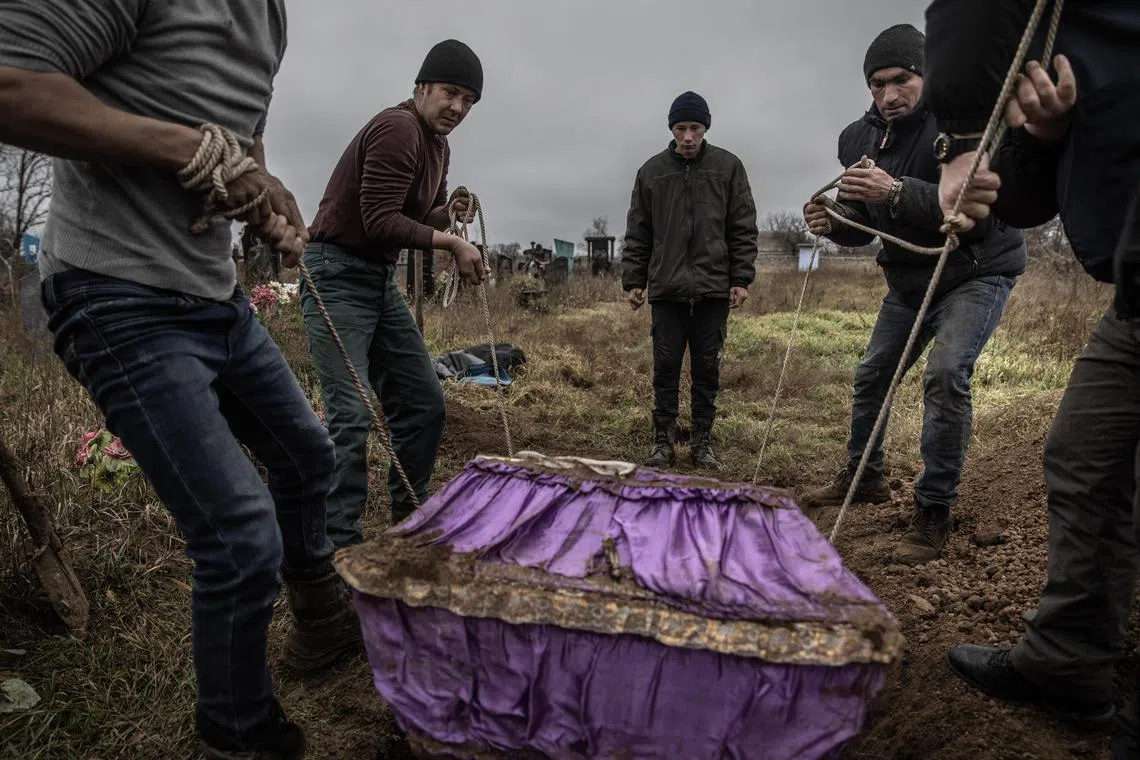 Local residents help police and war crimes investigators exhume the body of a 15-year-old girl, who local residents said had been executed by Russian forces, in the liberated village of Pravdyne, on Nov 29, 2022.