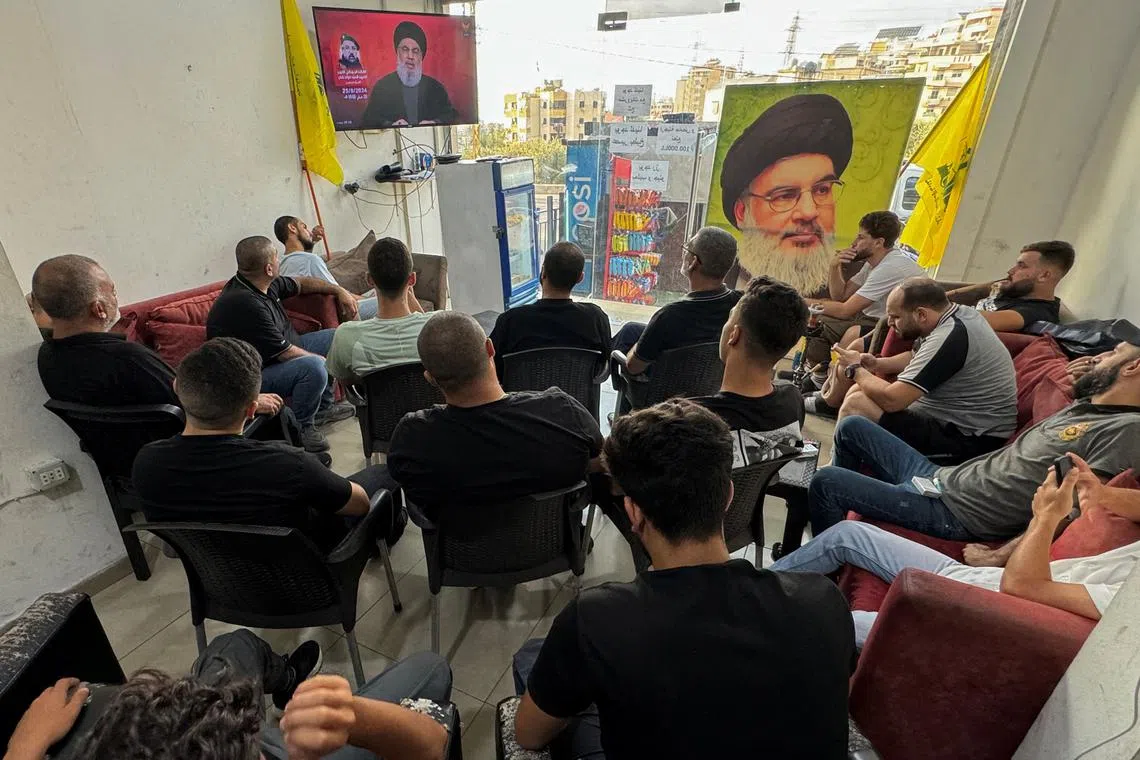 People watch Lebanon's Hezbollah leader Sayyed Hassan Nasrallah delivering a televised address, as they sit at a cafe in Sidon, Lebanon August 25, 2024. REUTERS/Hassan Hankir