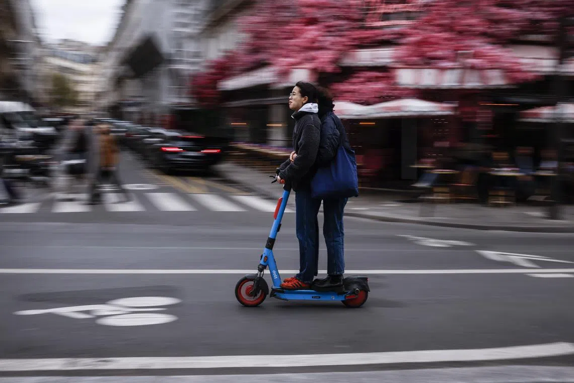 People ride a self-service e-scooter in Paris, France, 01 April 2023. On 02 April Paris residents will be able to vote whether to ban self-service scooters in use in the city.  EPA-EFE/YOAN VALAT