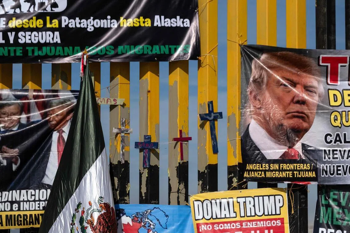 Crosses and protest banners depicting US President Donald Trump hang on the Mexico side of the Mexico–US border wall.