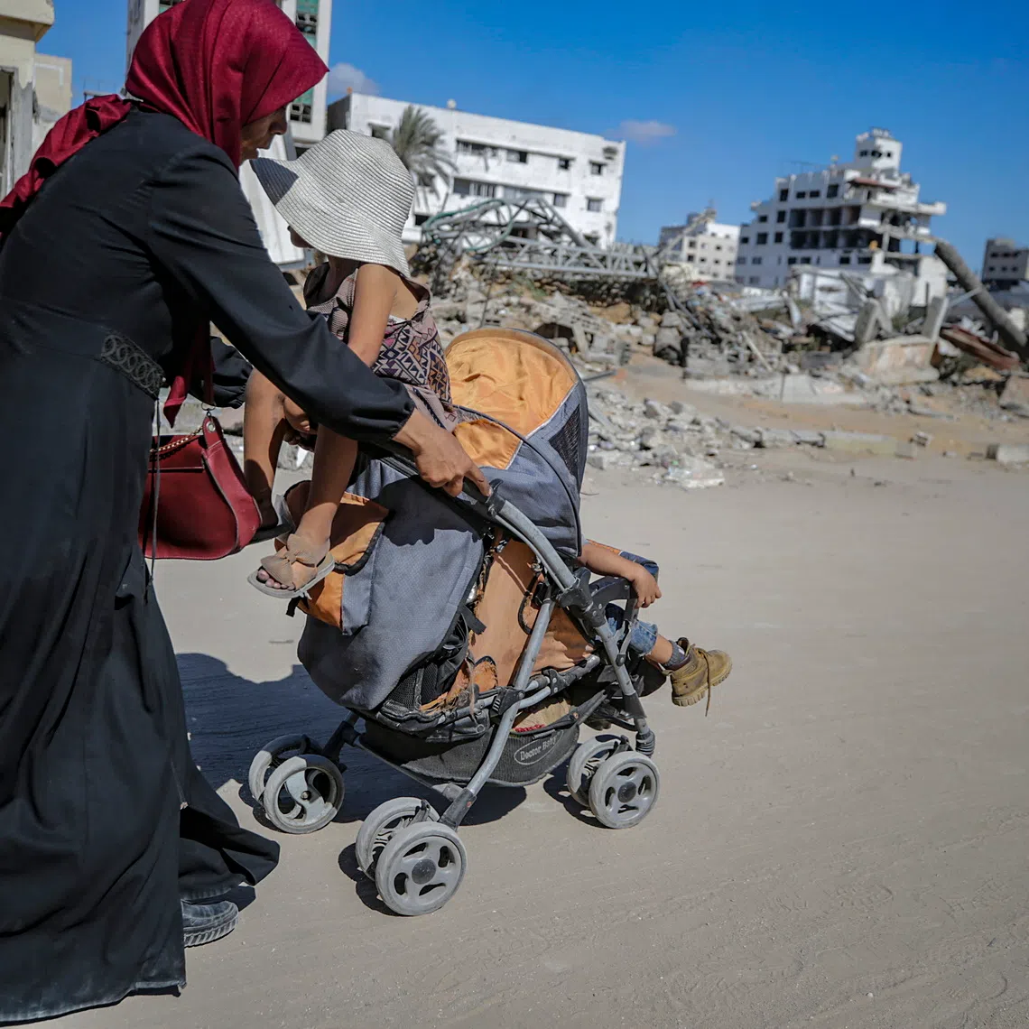 A Palestinian mother flees with her children following an Israeli airstrike during an Israeli military operation in Gaza City.