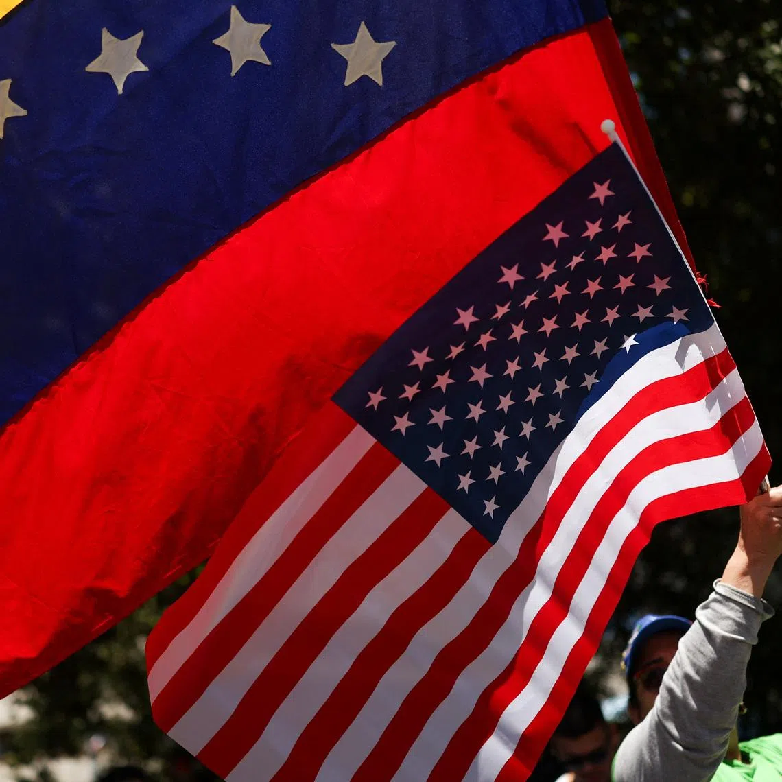 A person waves U.S. and Venezuela's flags as people celebrate following a U.S. strike on Venezuela where President Nicolas Maduro and his wife, Cilia Flores, were captured, in Santiago, Chile January 3, 2026. REUTERS/Pablo Sanhueza/File Photo