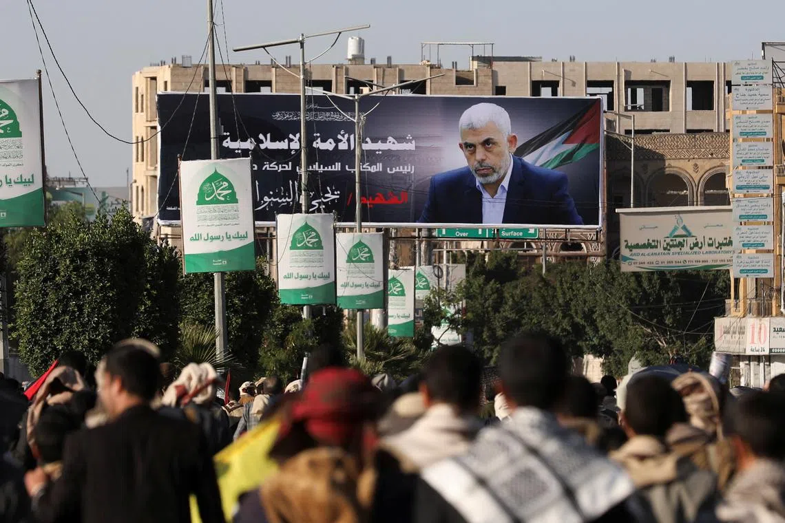 People walk past a billboard portraying the late Hamas leader Yahya Sinwar at the site of a rally held by protesters, mainly Houthi supporters, to show support to Lebanon's Hezbollah and Palestinians in the Gaza Strip, in Sanaa, Yemen October 18, 2024. REUTERS/Khaled Abdullah