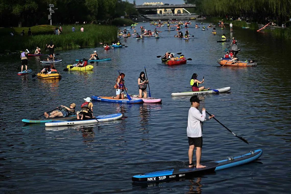 TOPSHOT - People paddle on the Liangma river in Beijing on June 15, 2025. (Photo by Pedro PARDO / AFP)
