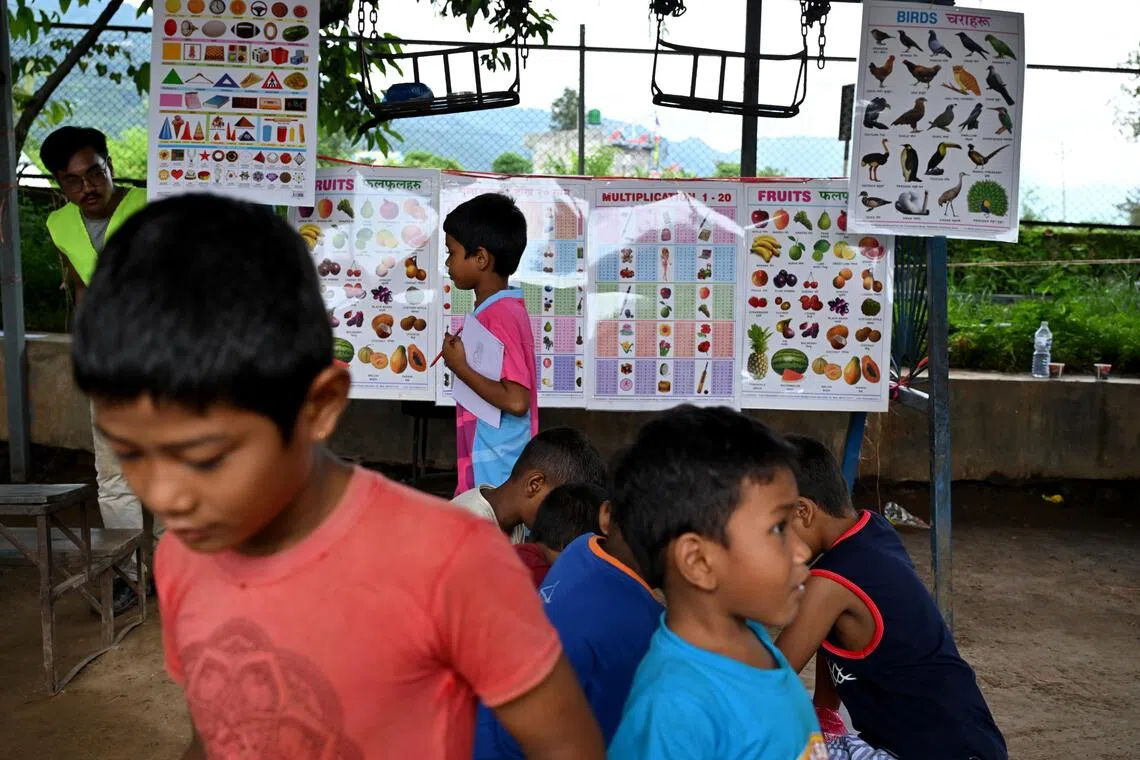 Displaced children play with posters and toys donated by Nepali locals in an evacuation centre in Devighat after deadly flash floods tore through the region on Aug 26.