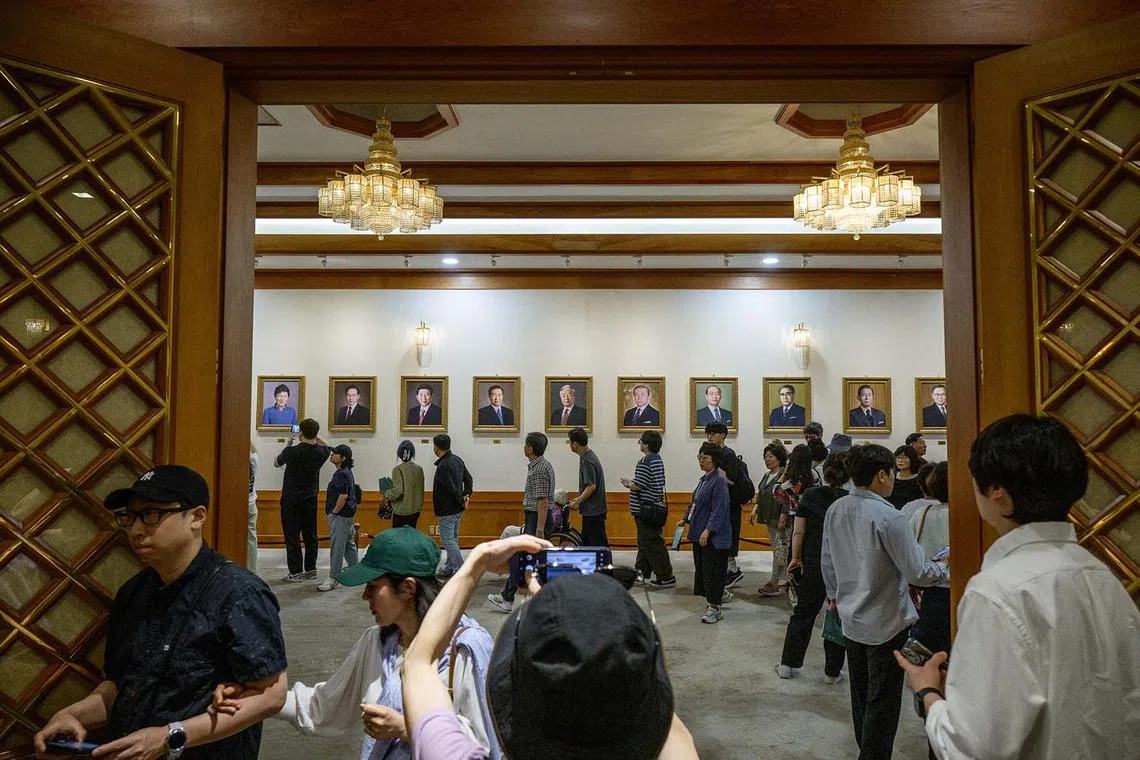 TOPSHOT - People look at painted portraits of former South Korean presidents at the Blue House in Seoul on June 9, 2025, named for the approximately 150,000 hand-painted blue tiles that adorn its roof, that had been home to South Korea's leaders for seven decades until 2022, when former impeached president Yoon Suk Yeol moved out to settle in what was then the Defence Ministry headquarters, about 6 kilometres away. Tens of thousands of South Koreans poured into the Blue House in northern Seoul on June 9, as it could be their last chance to visit the premise as a new president is poised to return to the former presidential office. (Photo by ANTHONY WALLACE / AFP)