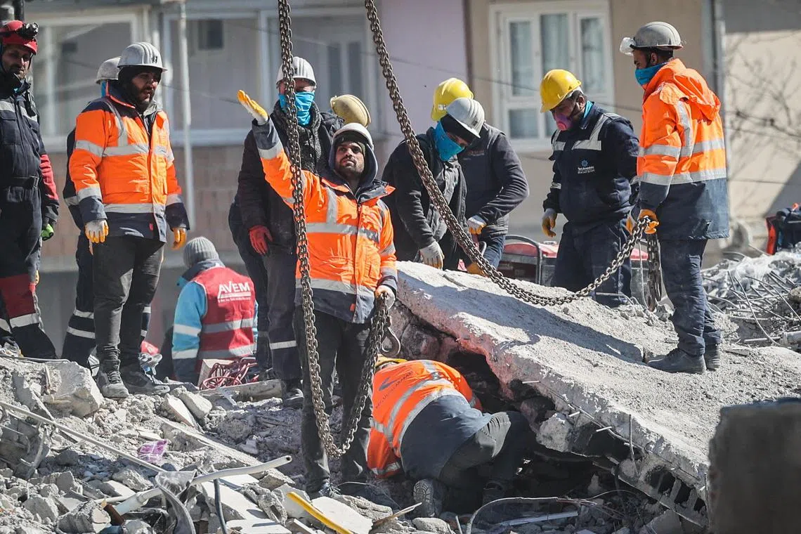 Search and rescue team members work among the rubble of a collapsed building in the aftermath of an earthquake in Nurdagi, southeastern Turkey, on Feb 13, 2023. 