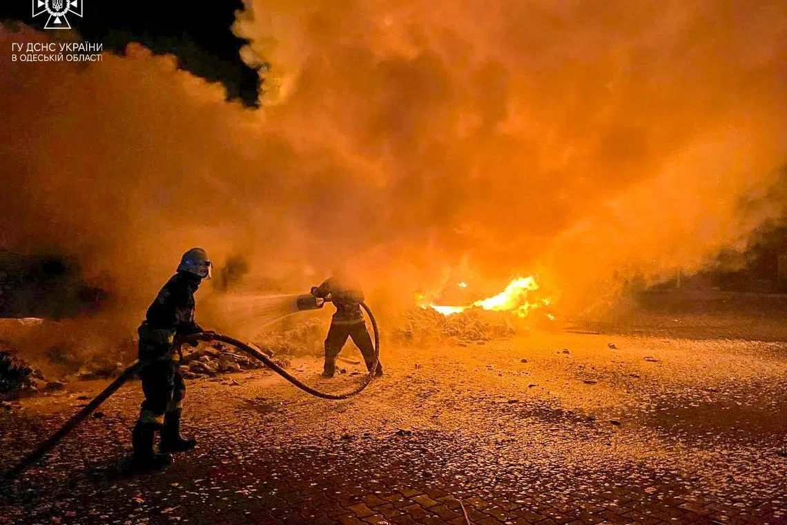 Firefighters extinguish burning trucks damaged during a Russian drone attack on a port in the Odessa region.