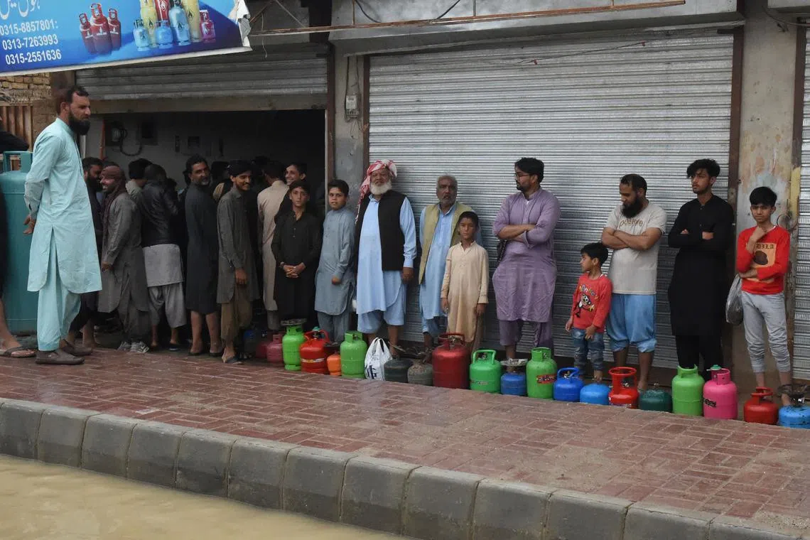 Residents stand in a queue to fill cooking gas cylinders after heavy monsoon rainfalls in Quetta on Aug 26, 2022.