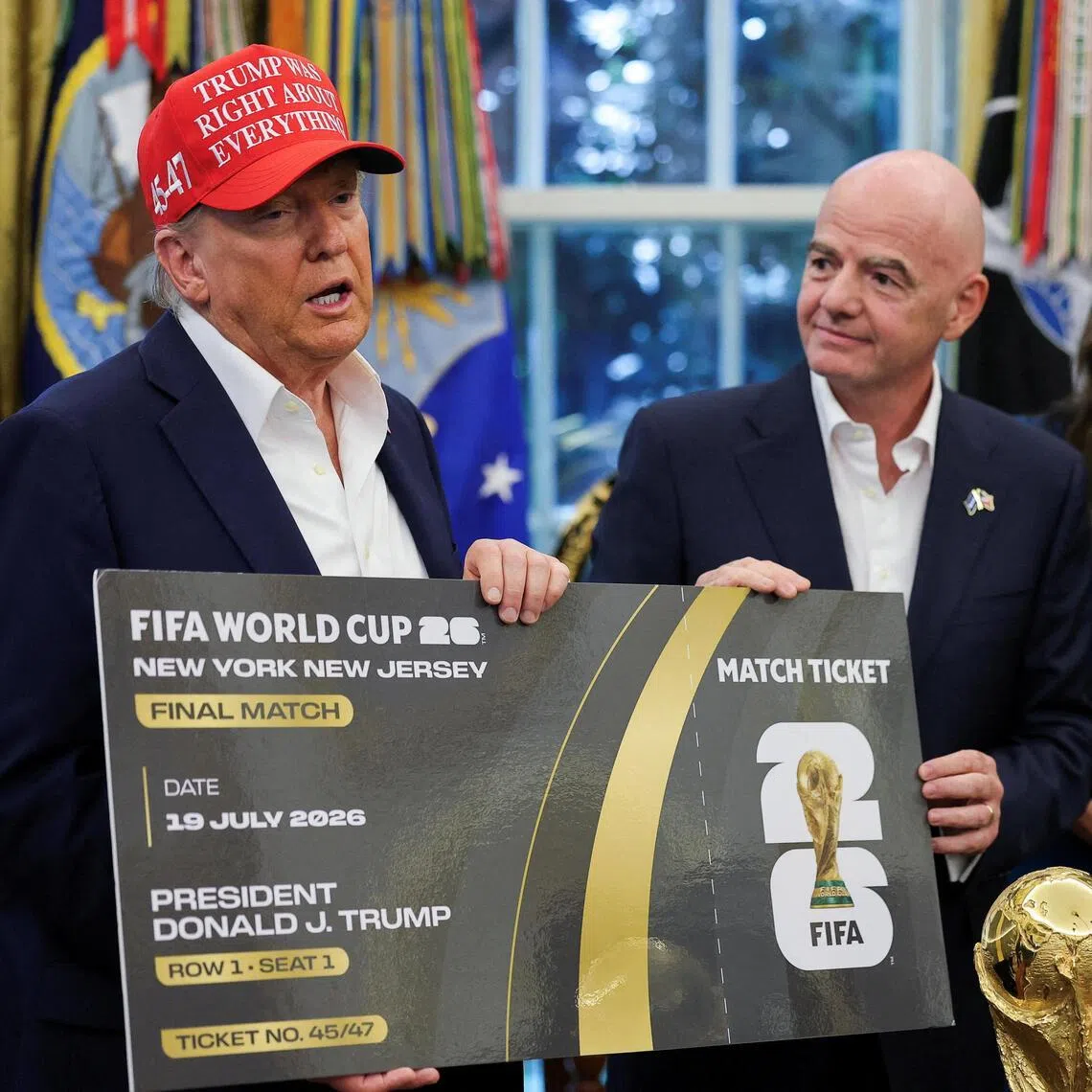 US President Donald Trump and FIFA president Gianni Infantino holding a 2026 World Cup final match ticket that was presented to President Trump, as he makes an announcement on the showpiece, while US Homeland Security Secretary Kristi Noem looks on in the White House in August 2025.
