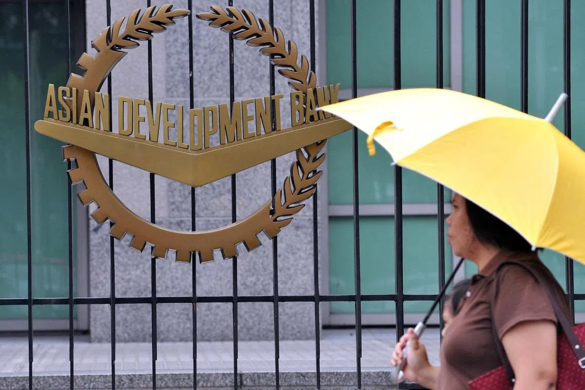 (FILES) In this file photo taken on September 2, 2010, a pedestrian walks past a logo of the Asian Development Bank (ADB) displayed outside its headquarters in Manila. The Asian Development Bank cut its inflation forecast for developing Asia on July 19, 2023, as food and fuel prices eased, supply-chain disruptions waned and interest rate hikes started to bite. (Photo by TED ALJIBE / AFP)