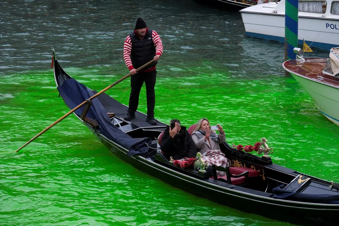 People enjoy a gondola ride on the Grand Canal, where the canal's water has been dyed green in a protest organised by the "Extinction Rebellion" climate activists, in Venice, Italy, November 22, 2025. REUTERS/Manuel Silvestri     TPX IMAGES OF THE DAY     