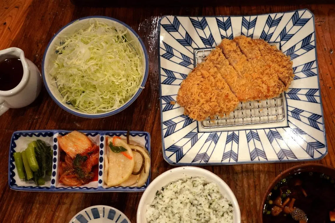TOPSHOT - This photo taken on January 21, 2025 shows a pork cutlet dish served with shredded cabbage (top 2nd L) at the restaurant Katsukichi in Tokyo. The 2024 record summer heat and heavy rain ruined crops, driving up the cost of the usually inexpensive leafy green in what Japanese media has dubbed a "cabbage shock". (Photo by Kazuhiro NOGI / AFP) / TO GO WITH: Japan-economy-agriculture-climate-inflation, REPORTAGE by Tomohiro Osaki and Hieun Shin