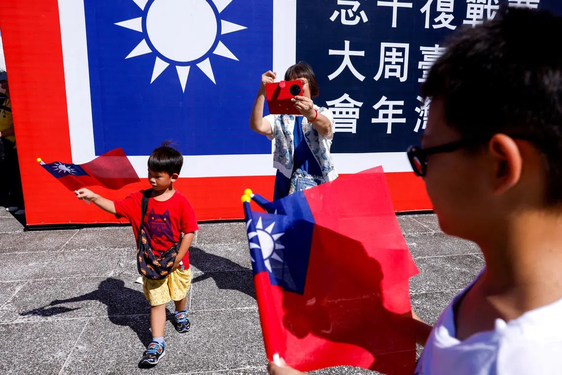 People hold Taiwanese flags during an event to commemorate the 80th anniversary of the end of World War Two at Chiang Kai-shek Memorial Hall in Taipei, Taiwan August 16, 2025. REUTERS/Ann Wang