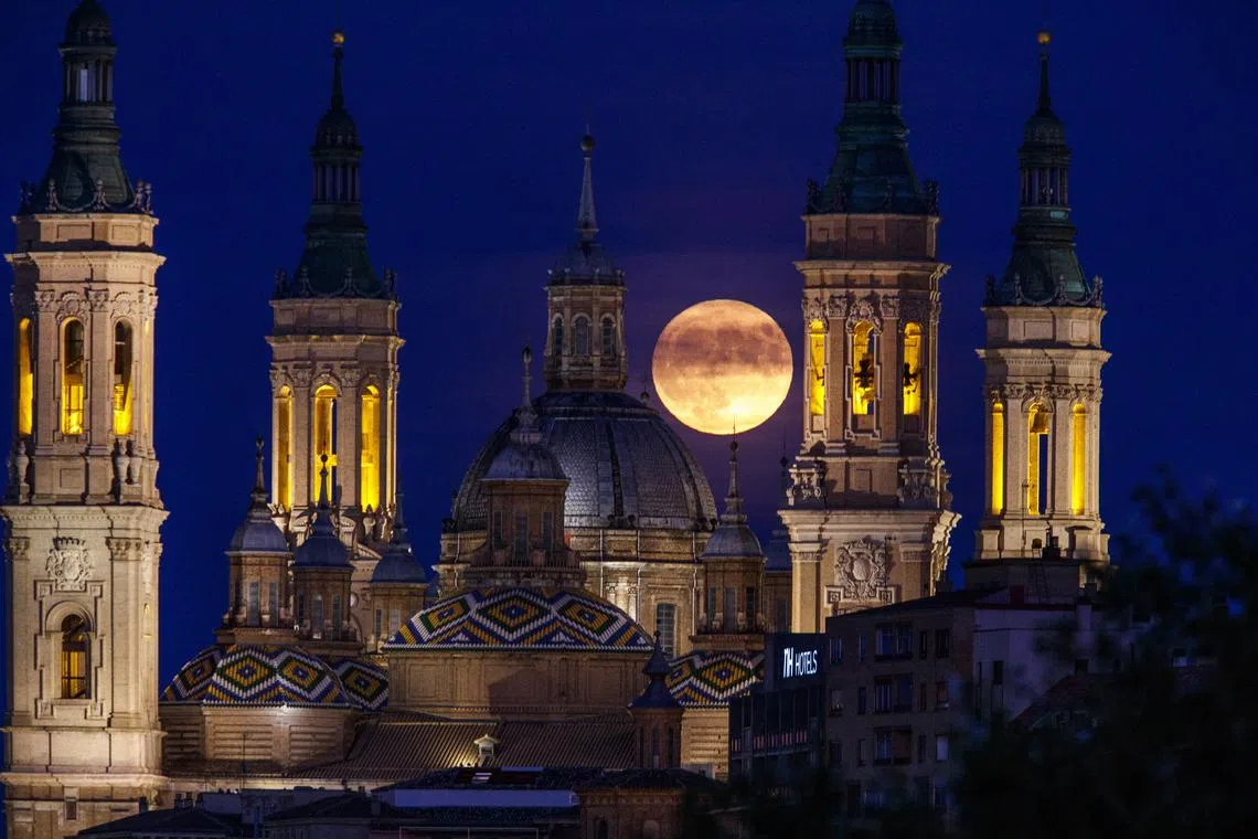 A full blue moon rising over El Pilar Basilica in Zaragoza, Spain, on 30 Aug, 2023.