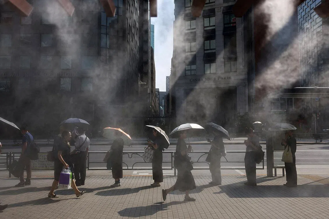 People exposed to the sun hold parasols as they wait for a bus near a cooling mist as the Japanese government issued a heatstroke alert in Tokyo and other prefectures, in Tokyo, Japan July 9, 2025. REUTERS/Issei Kato TPX IMAGES OF THE DAY