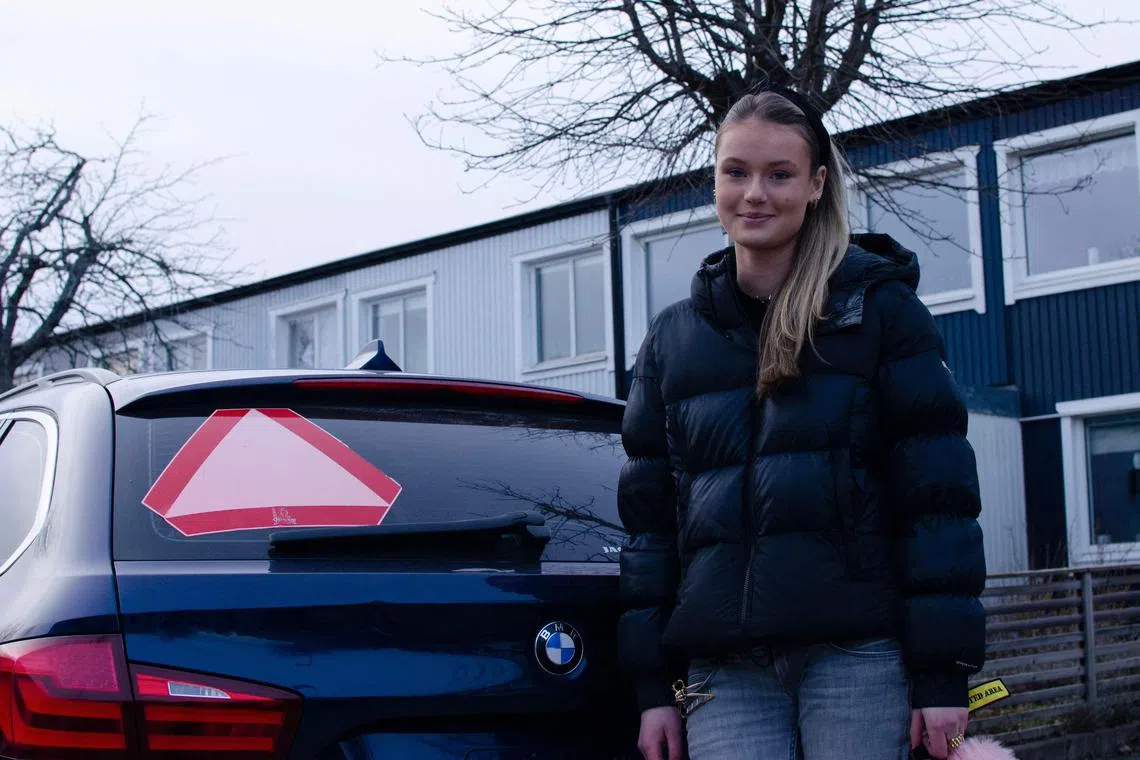 Evelina Christiansen, 15, in front of her dark blue 5-series BMW in the driveway of her family’s home in Stockholm. 