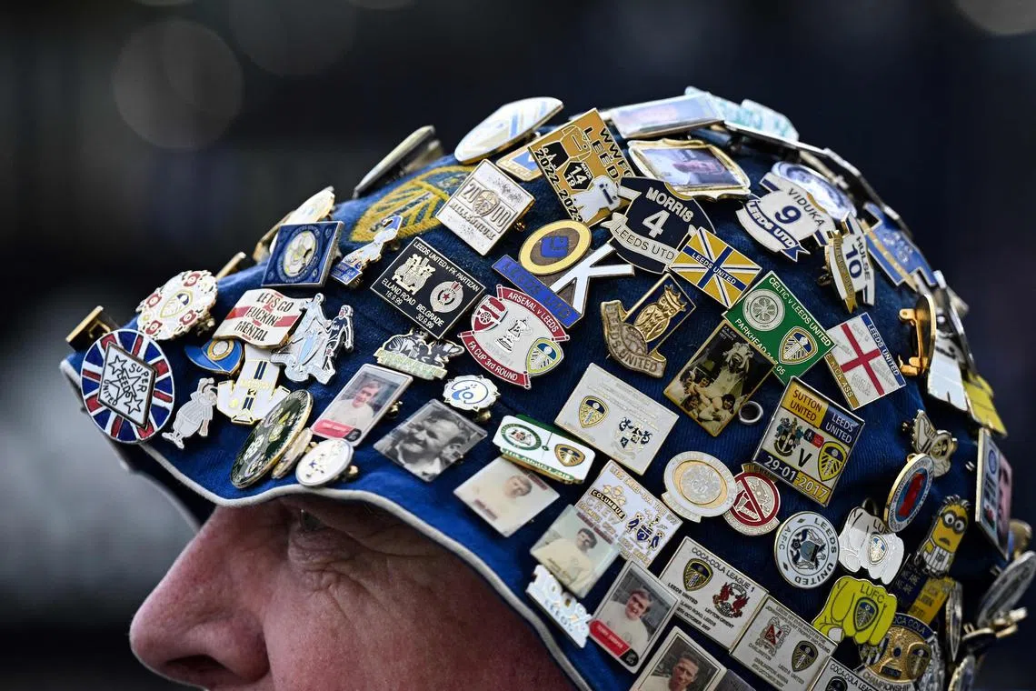 A Leeds' fan wearing a hat covered in pins arrives prior to the English Premier League football match between Leeds United and Leicester at Elland Road in Leeds, northern England on April 25, 2023. 