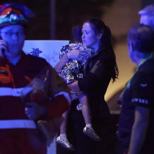 A woman a child in a blanket after a shooting incident at Bondi Beach in Sydney on Dec 14.