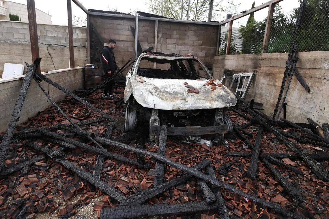 A Palestinian inspects a burnt-out car following an attack by Israeli settlers in the village of Deir al-Hatab in the Israeli-occupied West Bank on March 23, 2026. 
