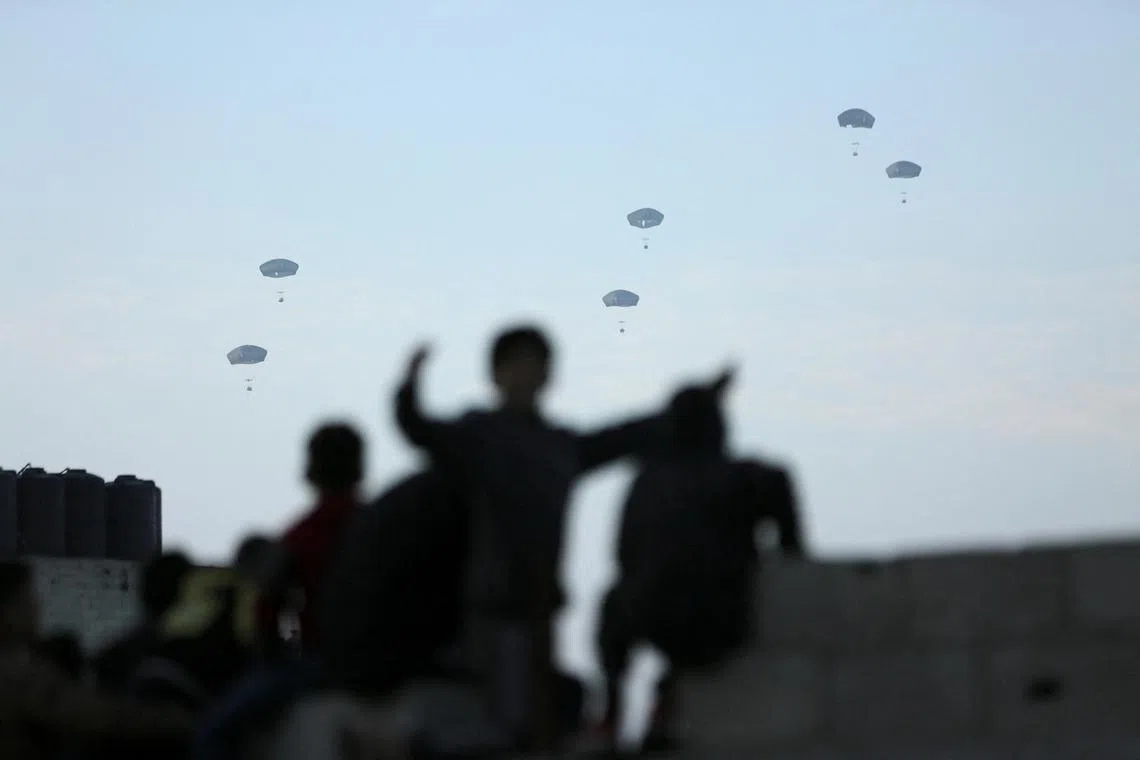 FILE PHOTO: People watch as U.S. military carries out its first aid drop over Gaza, amid the ongoing the conflict between Israel and the Palestinian Islamist group Hamas, in Gaza City, March 2, 2024. REUTERS/Kosay Al Nemer/File photo