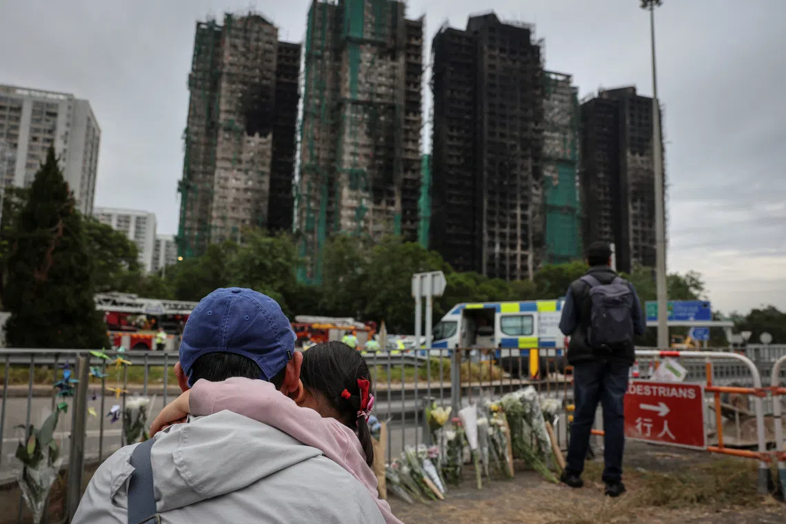 People pay tribute in front of the Wang Fuk Court housing complex following the deadly fire.