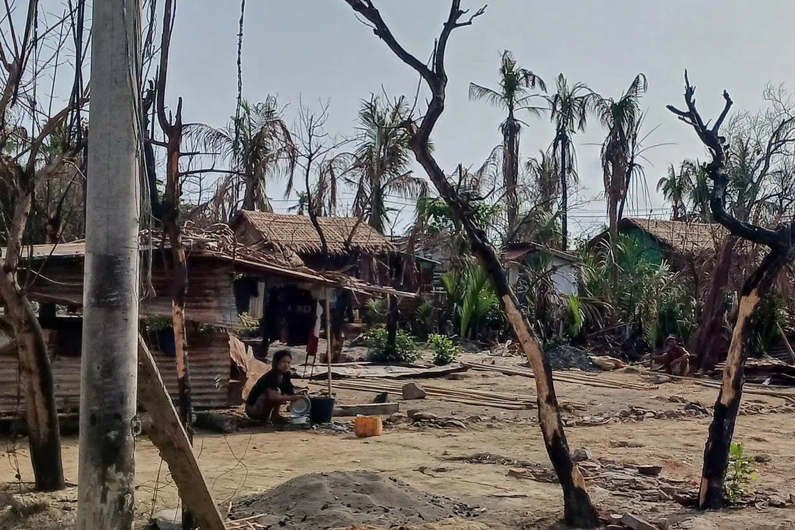 (FILES) This photo taken on May 21, 2024 shows a woman cooking next to destroyed houses and burned trees following fighting between Myanmar's military and the Arakan Army (AA) ethnic minority armed group in a village in Minbya Township in Rakhine State. The charity Doctors Without Borders will halt medical activities in northern Rakhine state in Myanmar due to an "extreme escalation of conflict" between an ethnic armed group and the military, it said on June 27. (Photo by AFP)