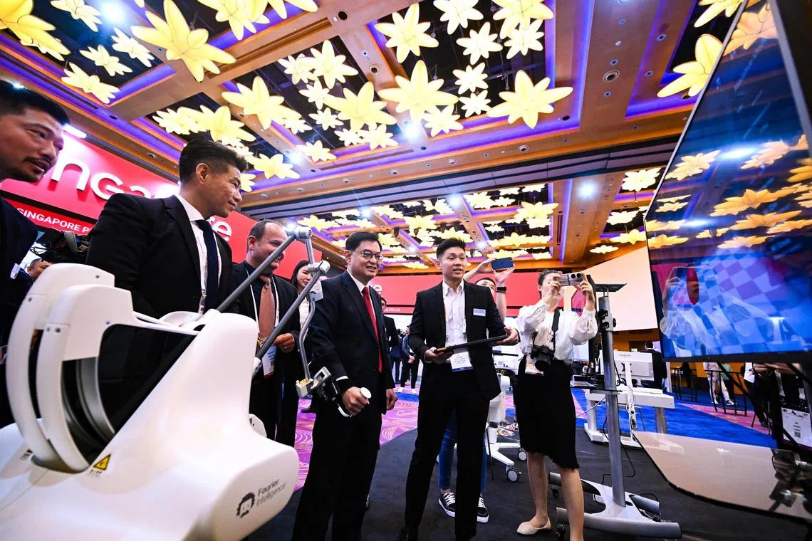 DPM Heng Swee Keat (third from right) tries the ArmMotus EMU upper limb training robot at RehabWeek 2023.