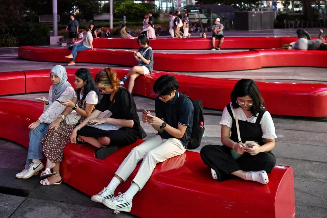 Generic pix of shoppers busy on their mobile phones while resting on benches outside the Ion Orchard shopping mall on Oct 3, 2023.
