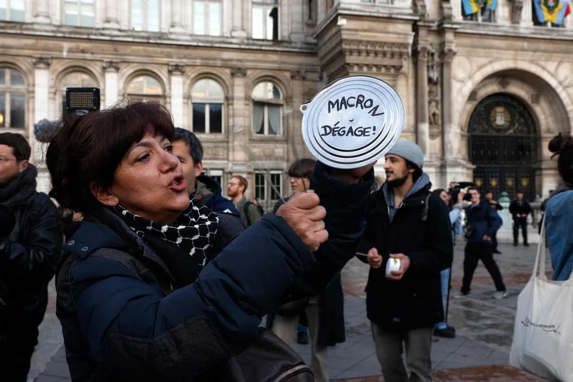 A protester banging a pan reading "Macron out" in front of Paris' city hall during a demonstration on April 24.