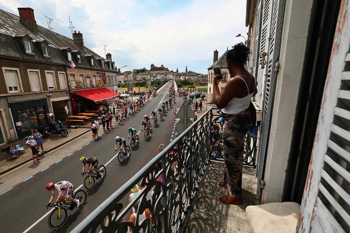 TOPSHOT - The pack of riders (peloton) cycles in Decize during the 12th stage of the 113th edition of the Tour de France cycling race, 181 km between Circuit de Nevers Magny-Cours and Chalon-sur-Saône in central France, on July 16, 2026. (Photo by Anne-Christine POUJOULAT / AFP)