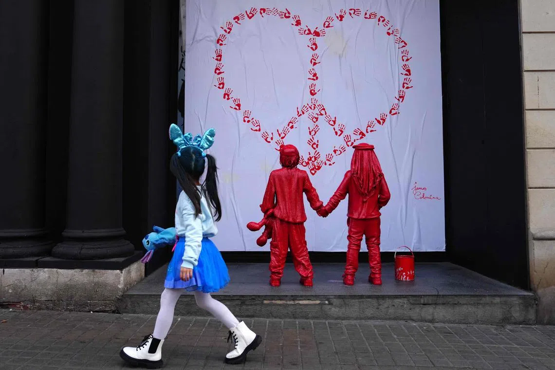 Newly installed sculpture, by French street artist James Colomina, which depicts two kids holding hands, one of them wears a Jewish kippah while the other wears a Palestinian keffiyeh, and looking at a heart-shaped CND peace sign made with red hand prints, in Barcelona on Feb 8, 2024. 