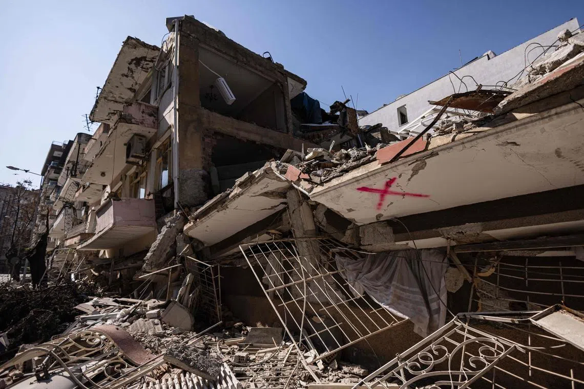 This photograph taken on February 18, 2023 shows a sign (X) in read which refers to a buildings that has been already scanned by rescue workers in the city of Antakya. - A 7.8-magnitude earthquake hit near Gaziantep, Turkey, in the early hours of February 6, followed by another 7.5-magnitude tremor just after midday. The quakes caused widespread destruction in southern Turkey and northern Syria and has killed more than 44,000 people. (Photo by Sameer Al-DOUMY / AFP)