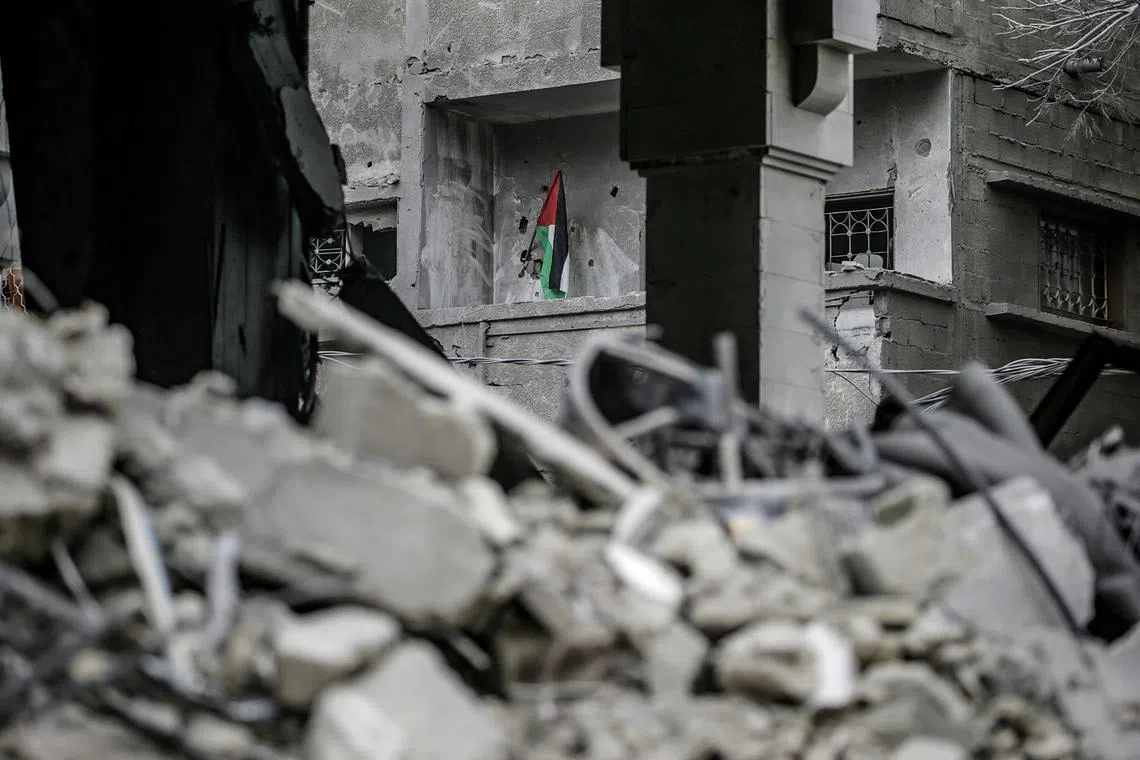 A Palestinian flag standing amid the rubble of a house destroyed by an Israeli air strike, in the central Gaza Strip, on Nov 27.