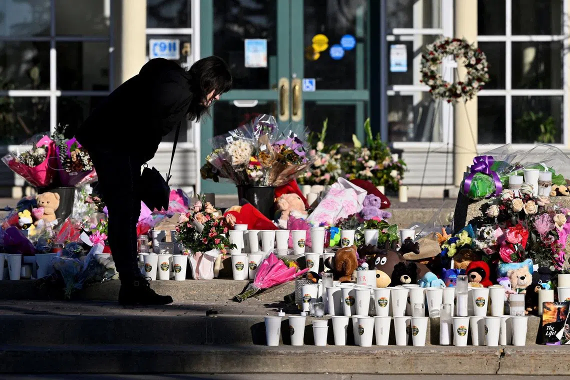 FILE PHOTO: A woman visits a growing makeshift memorial on the steps of the town hall, four days after one of the worst mass shootings in recent Canadian history, in the town of Tumbler Ridge, British Columbia, Canada, February 14, 2026. REUTERS/Jennifer Gauthier/File Photo