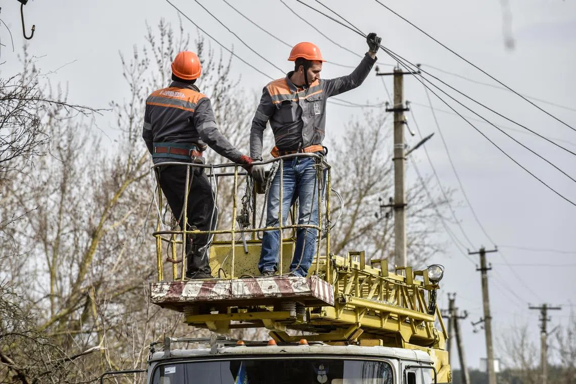 Workers repair power lines damaged by shelling, in Ukraine's Kharkiv region.