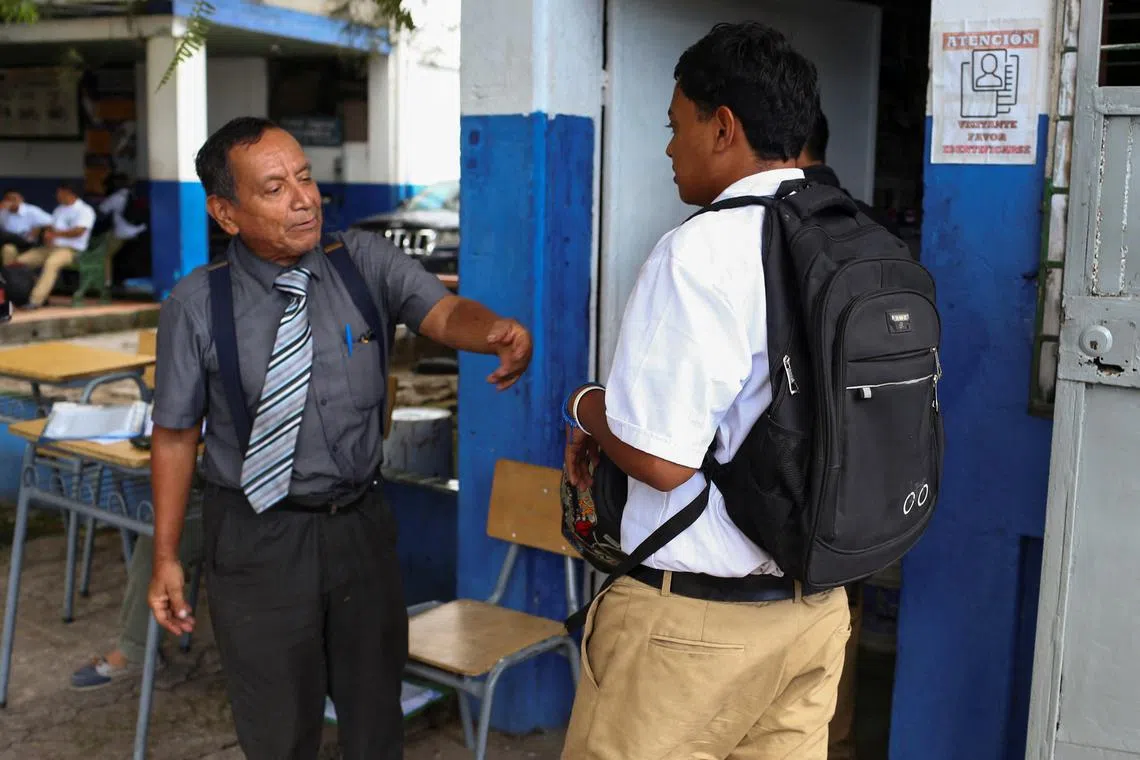 Principal Oscar Melara checks a student's uniform at Instituto Nacional Tecnico Industrial, as regulations over students' appearance and behaviour are enforced following a memorandum by the Ministry of Education, in San Salvador, El Salvador, August 21, 2025. REUTERS/Jose Cabezas