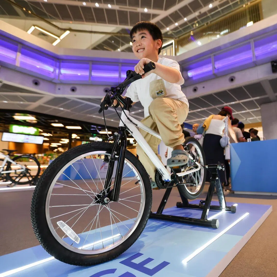 A young participant pedaling on a stationary bicycle to see how much energy they can generate at the Energy Market Authority interactive pop-up event at Funan Mall on Mar 16, 2026.