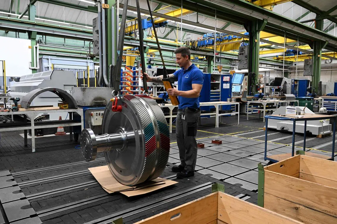 Employee Tobias Kasan works at a gear in a assembly hall of the German gear manufacturing company Renk in Augsburg, southern Germany, on May 8, 2023. - The RENK Group is one of the world's leading suppliers of highly efficient drive and control technology. They develop systems for using high forces and torques to drive vehicles, ships and machines. Customers come from the defense, energy and industrial sectors. (Photo by Christof STACHE / AFP)