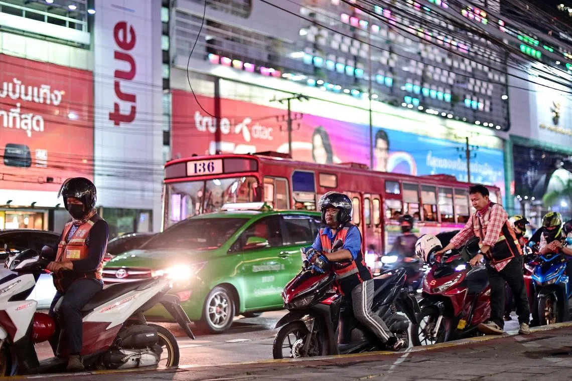Motorcyle-taxi riders wait for customers along a street in Bangkok on September 13, 2023. (Photo by MANAN VATSYAYANA / AFP)
