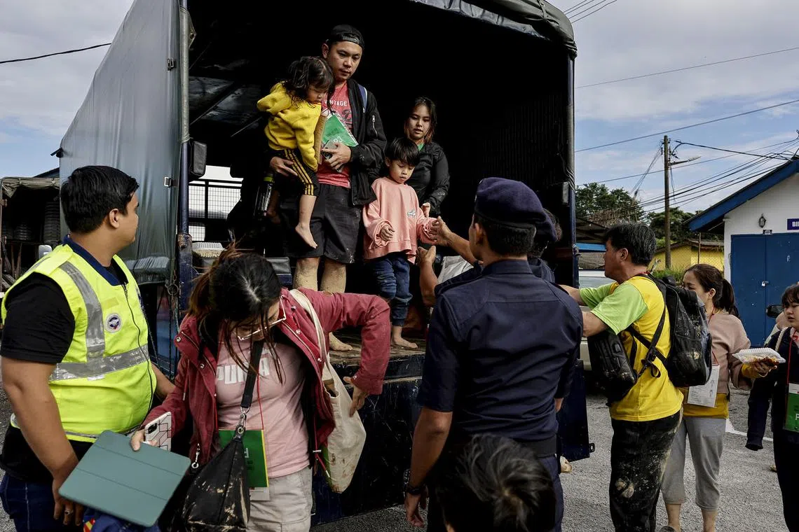 Singaporean Mr Tee Yeow King (in truck, left), carrying his daughter, and his wife (on the ground, second left) arriving at Ulu Yam Bharu police station after being rescued,  Dec 16, 2022.