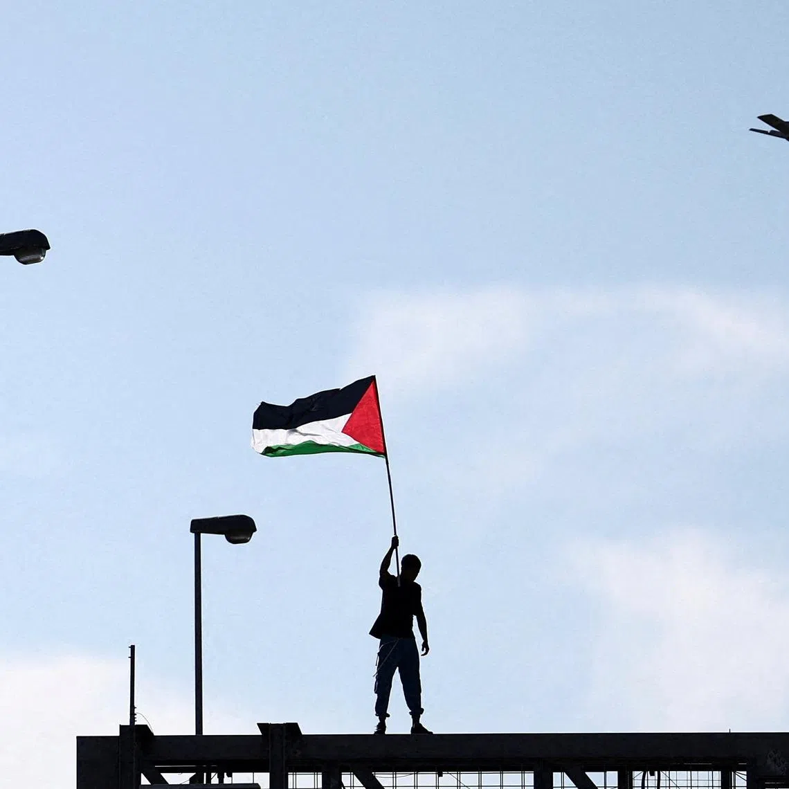 A pro-Palestinian demonstrator waves a Palestinian flag while protesting during a nationwide strike called by the USB union to condemn the Israeli forces' interception of the Global Sumud Flotilla vessels aiming to reach Gaza and break Israel's naval blockade, in Rome, Italy, October 3, 2025. REUTERS/Yara Nardi