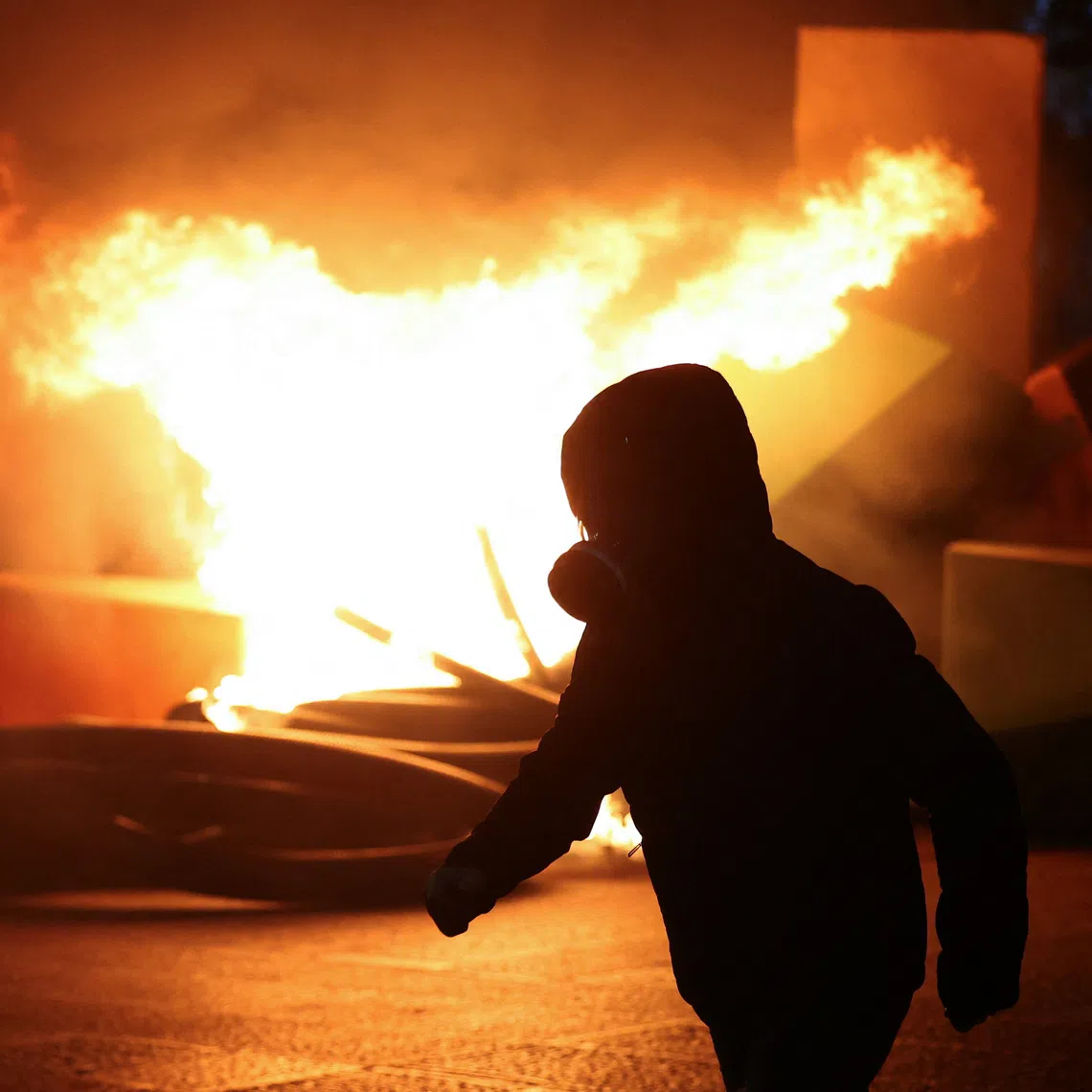A demonstrator walks with flames burning in the background, amid an anti-government protest by students in Tirana, Albania, October 16, 2026. REUTERS/Florion Goga