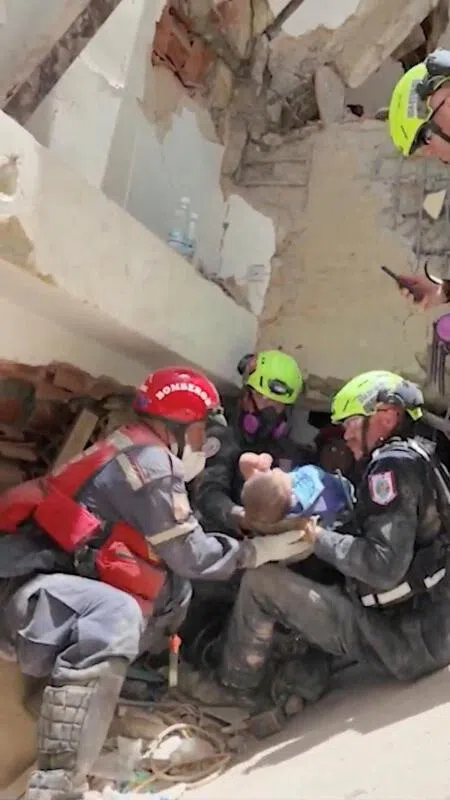 Emergency workers carrying a baby rescued from the rubble in the aftermath of the earthquakes in La Guaira, in a screengrab from a video released by the US Department of State.