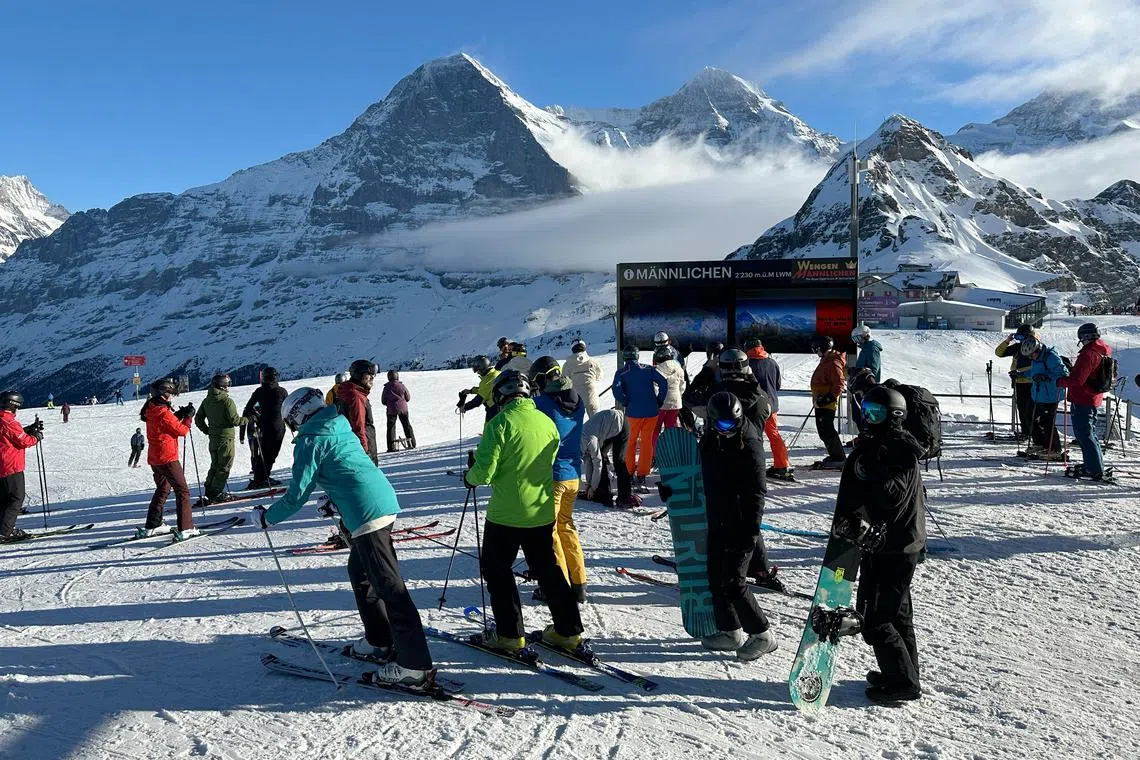 Skiers are pictured near a Mannlichen signboard in front of the Eiger and Monch mountains, in the alpine ski resort of Wengen, Switzerland, January 15, 2025. REUTERS/Denis Balibouse/ File Photo