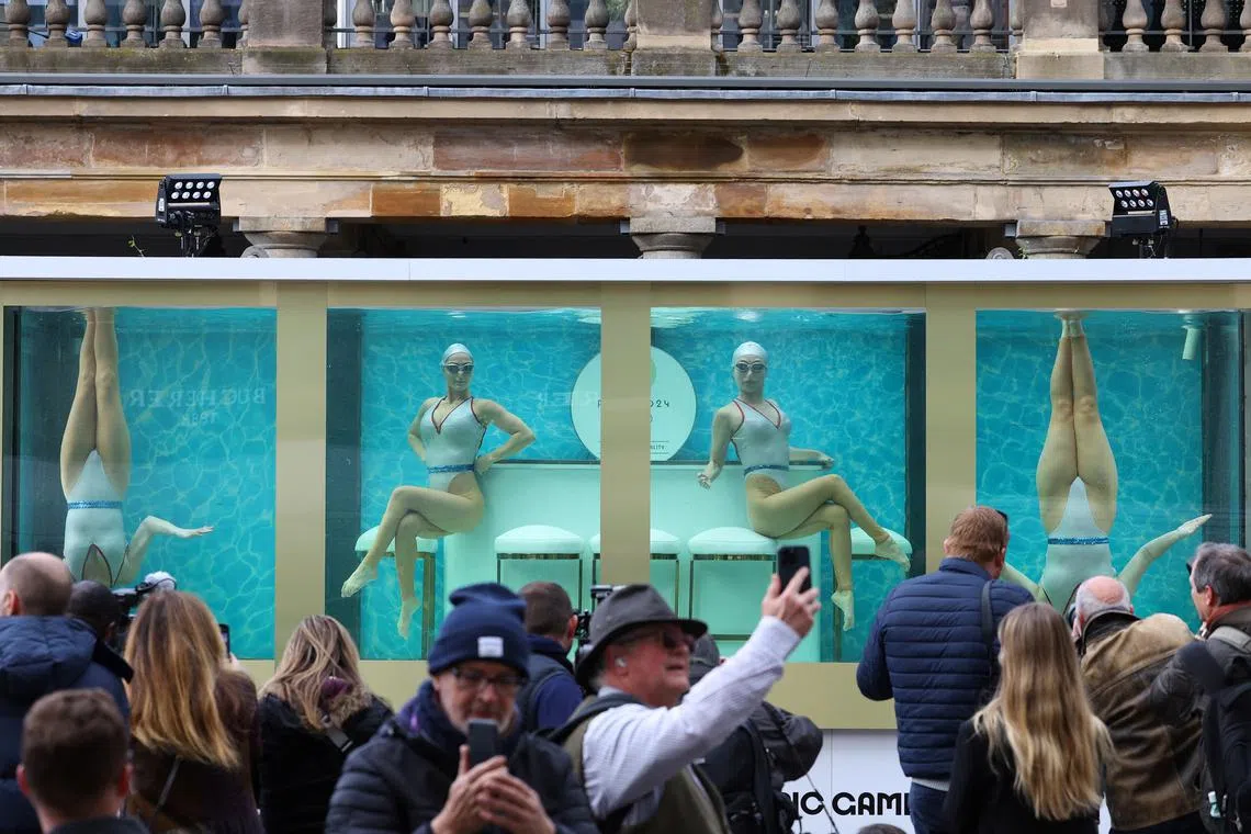 FILE PHOTO: People watch as former British Olympic artistic swimmers Asha George and Katie Clark together with Sisy Wang and Emily Kuhl, all of Aquabatix, perform in a large water tank to mark 100 days before the 2024 Paris Olympic Games starts, at Covent Garden in London, Britain, April 17, 2024. REUTERS/Toby Melville/File Photo