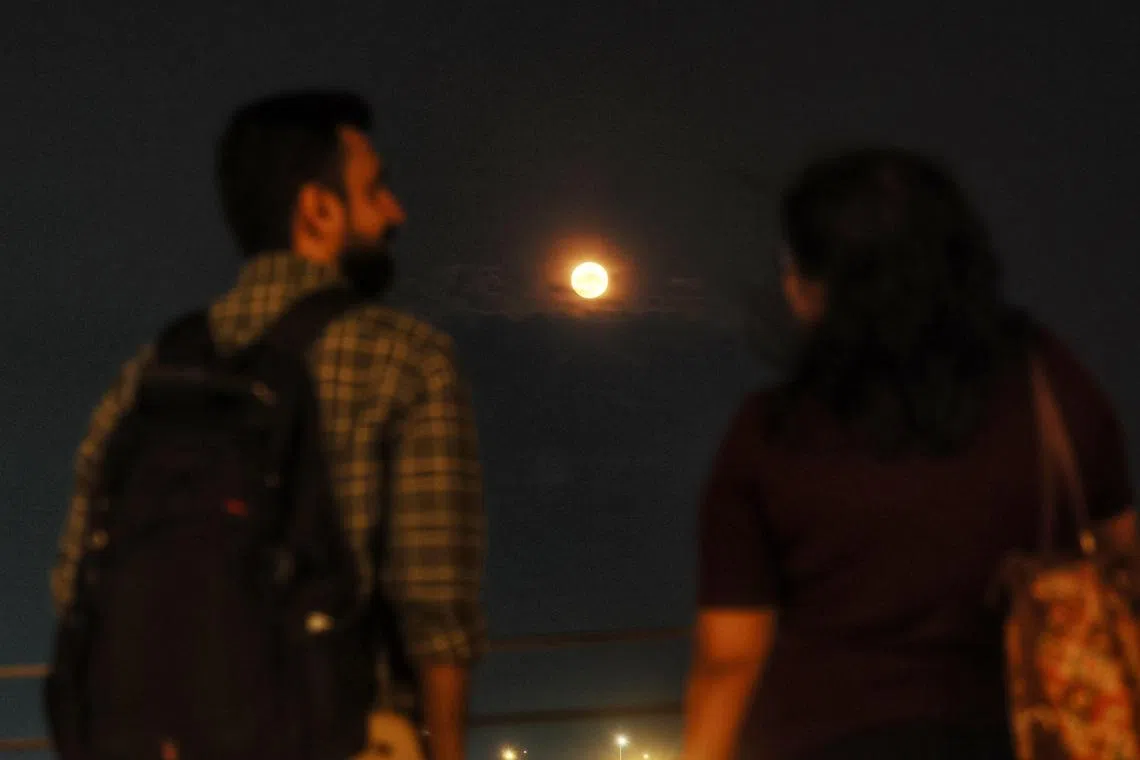 The super blue moon hovering between two sky gazers, captured near Merlion Park on Aug 31, 2023.